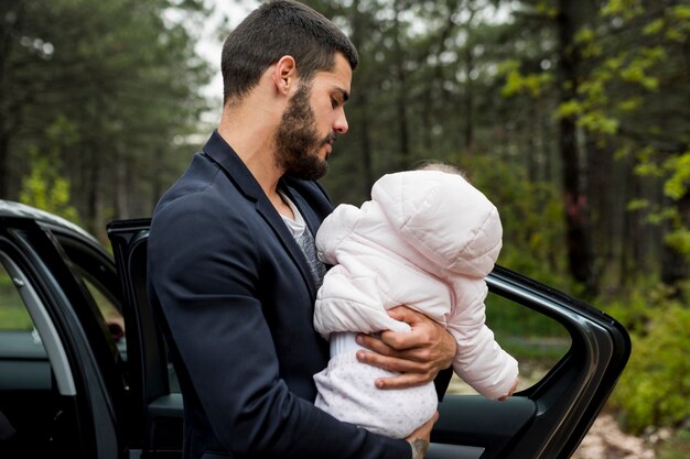 Bambino barbuto della tenuta del padre vicino all&#39;automobile