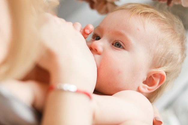 Bambino biondo che allatta al seno. Ritratto di testa di Close-up