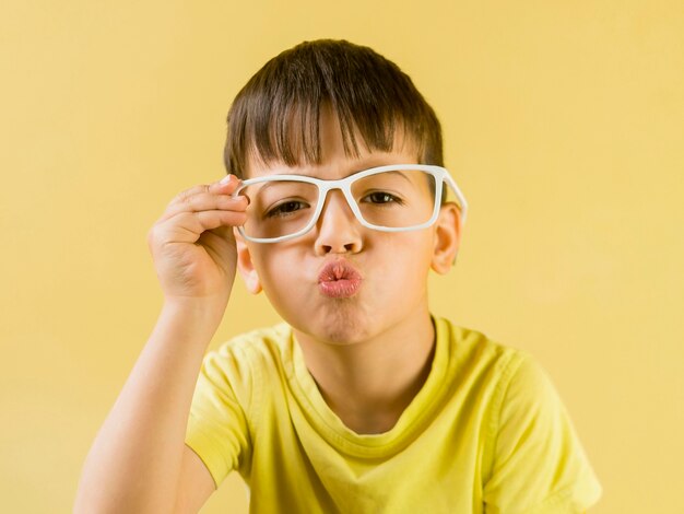 Bambino carino con gli occhiali e soffiando un bacio