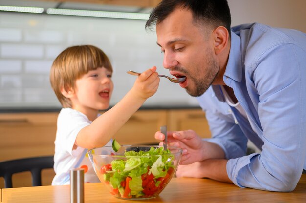 Bambino che dà a suo padre l'insalata da mangiare