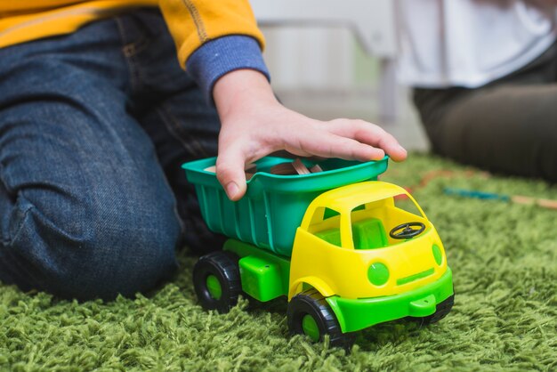 Bambino che gioca auto giocattolo sul pavimento