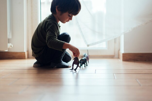 Bambino che gioca con dinosauri giocattolo