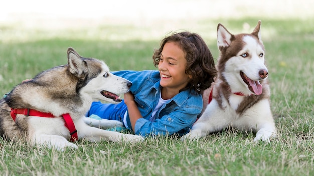 Bambino che gioca con i suoi cani mentre all'aperto con la famiglia