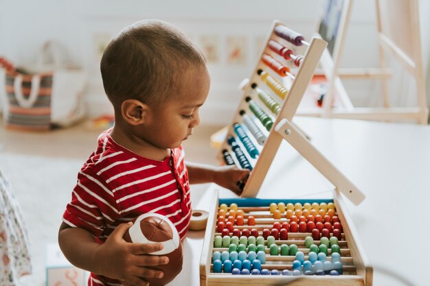 Bambino che gioca con un abaco di legno colorato