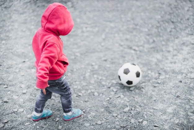 Bambino che gioca fuori con il calcio