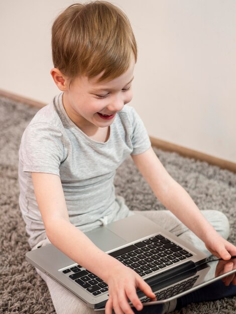 Bambino che gioca sul pavimento con il suo laptop