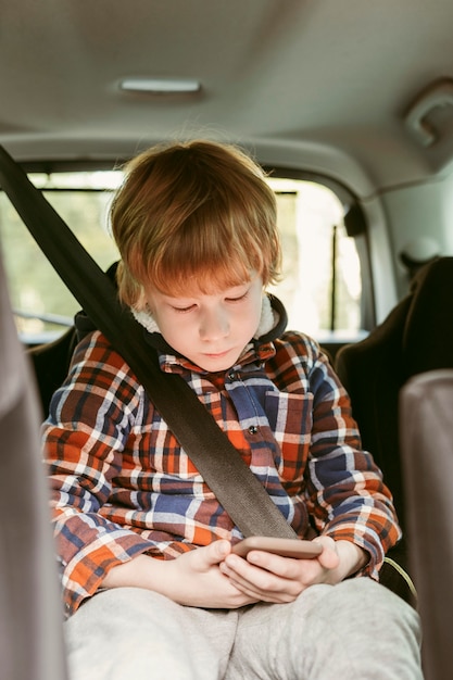 Bambino che gioca sullo smartphone in macchina durante un viaggio su strada