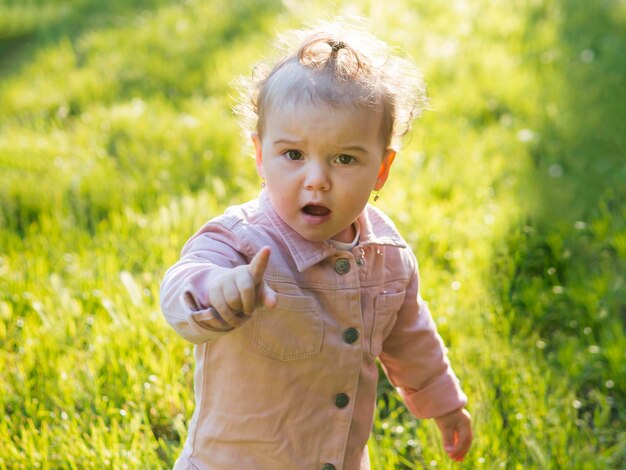 Bambino che indossa abiti rosa che mostra il dito indice