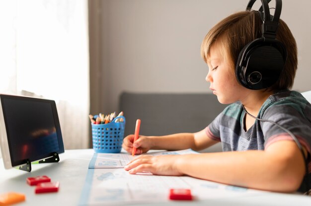 Bambino che indossa le cuffie che frequentano la scuola virtuale