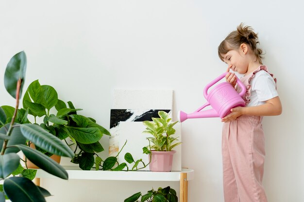 Bambino che innaffia le piante a casa