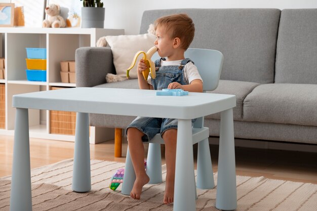 Bambino che mangia banana mentre gioca con il fidget