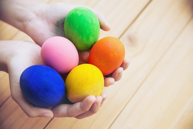 Bambino che mostra felicemente le uova di Pasqua variopinte - concetto di celebrazione di festa di Pasqua