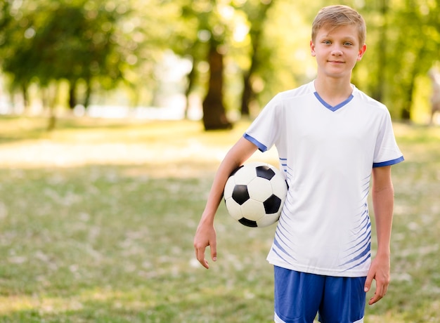 Bambino che tiene un calcio all'aperto