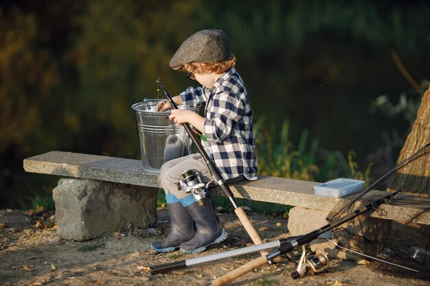 Bambino che tiene una canna da pesca Ragazzo che indossa una camicia a quadri Bambino che pesca d'estate