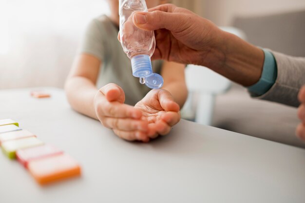 Bambino con disinfettante per le mani a casa prima della lezione