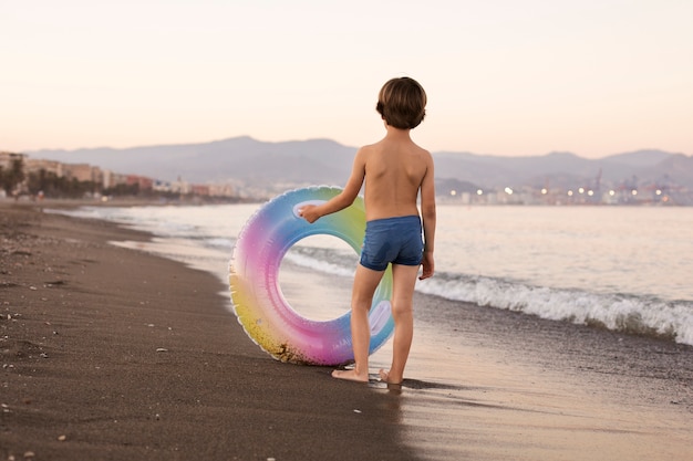 Bambino con galleggiante in riva al mare