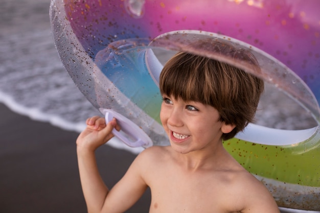 Bambino con galleggiante in riva al mare