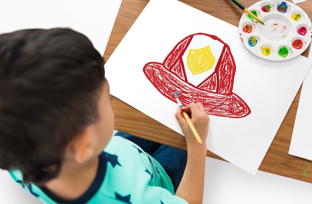 Bambino con un disegno del casco del pompiere