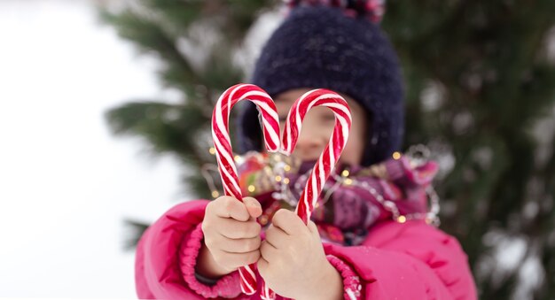 Bambino con un grande bastoncini di zucchero su sfondo sfocato. Concetto di vacanze invernali.