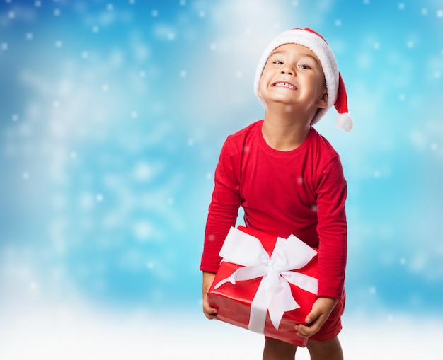 Bambino con un regalo con sfondo di neve