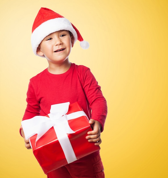 Bambino con un regalo rosso in uno sfondo giallo