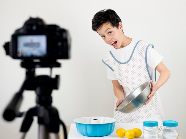 Bambino del colpo medio che cucina sulla macchina fotografica