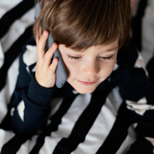 Bambino del primo piano che parla sul telefono