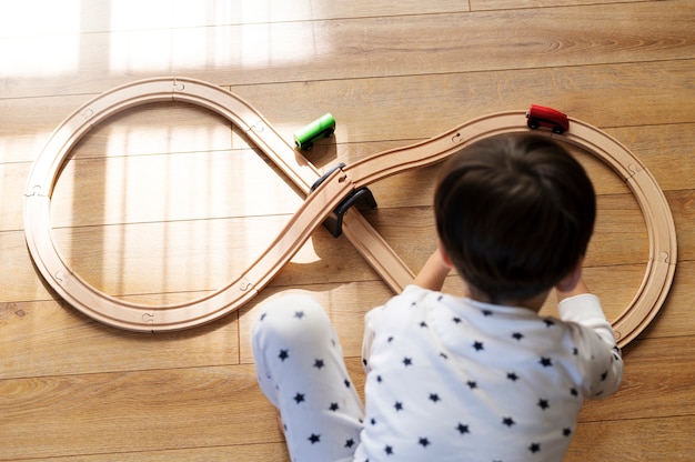 Bambino del tiro medio che gioca con l'auto di legno