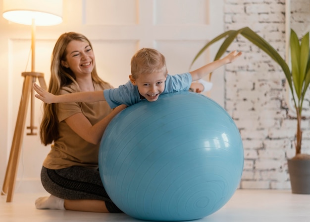 Bambino della holding della donna del colpo completo sulla palla della palestra