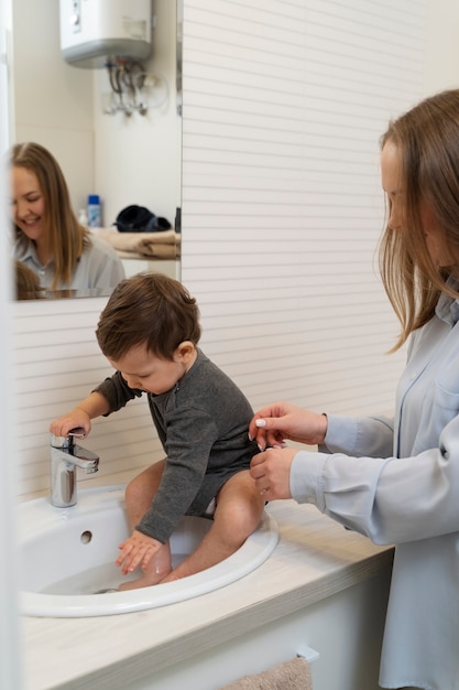 Bambino di balneazione della madre di vista laterale nel lavandino