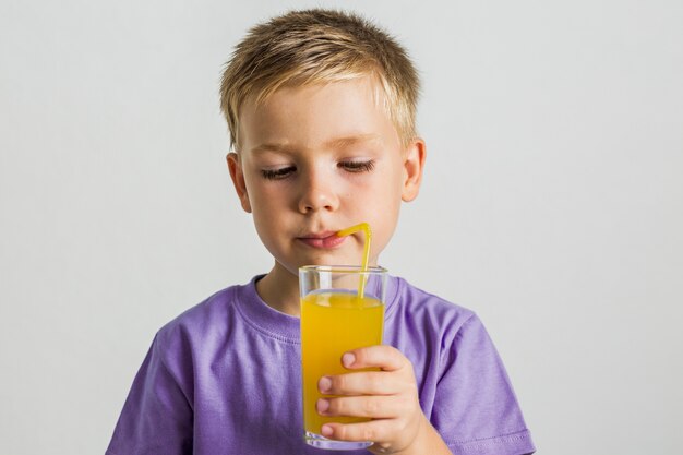 Bambino di vista frontale che beve il succo con una cannuccia