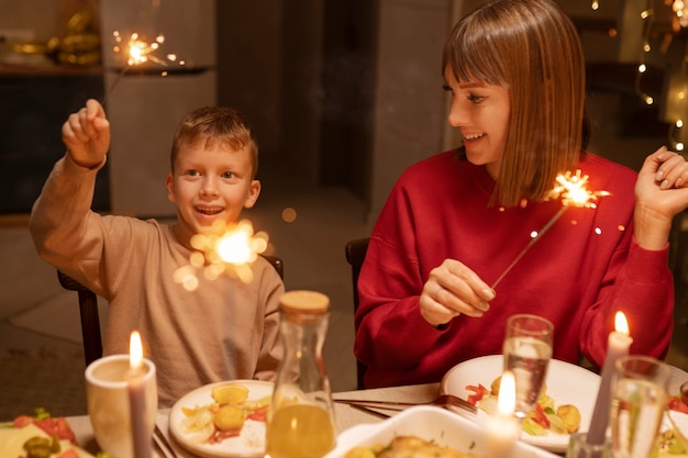 Bambino di vista frontale e madre che tengono fuochi d'artificio