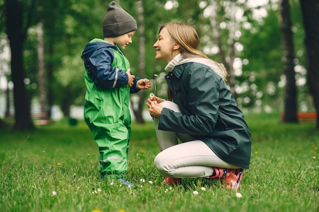 Bambino divertente in stivali da pioggia che giocano in un parco di pioggia