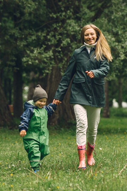 Bambino divertente in stivali da pioggia che giocano in un parco di pioggia