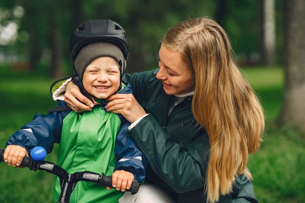 Bambino divertente in stivali da pioggia che giocano in un parco di pioggia