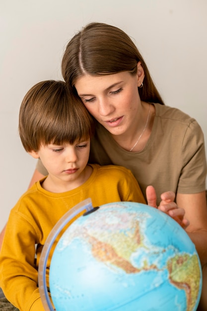 Bambino e madre che esaminano insieme globo