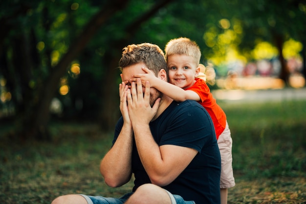 Bambino felice che copre gli occhi di suo padre