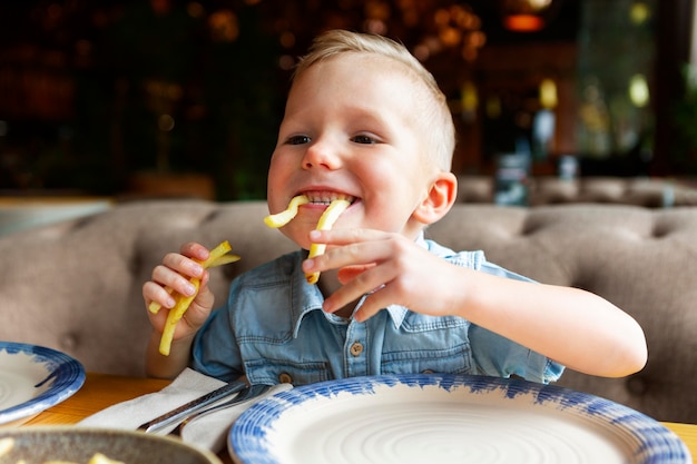 Bambino felice che mangia patatine fritte