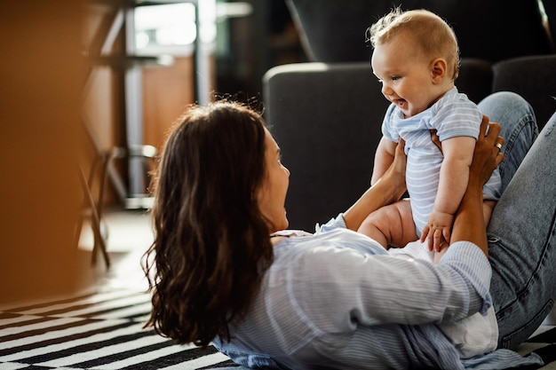 Bambino felice che si diverte a tempo con la madre sul pavimento di casa