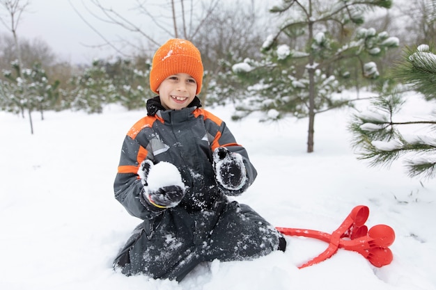 Bambino felice del colpo pieno che gioca con la neve