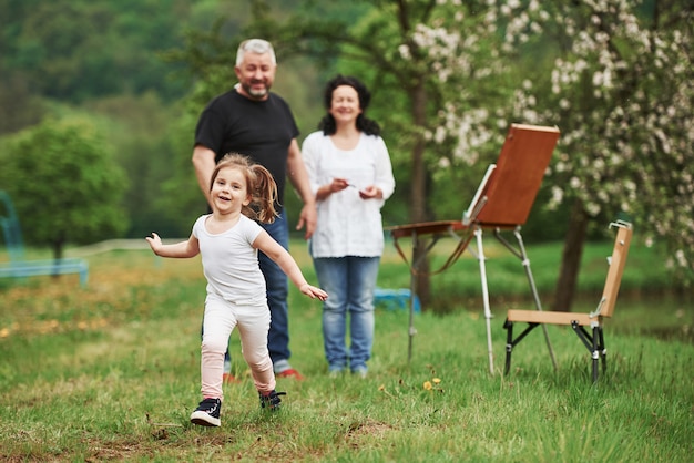 Bambino felice divertente. Nonna e nonno si divertono all'aperto con la nipote. Concezione della pittura