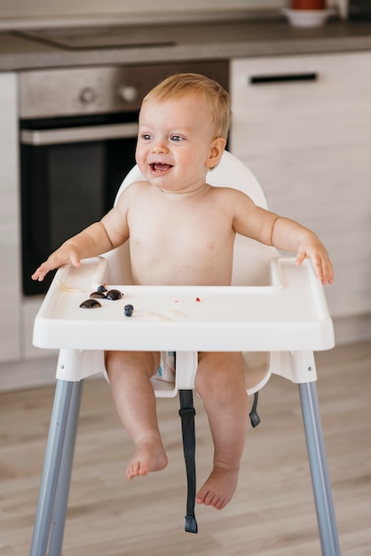 Bambino felice nel seggiolone scegliendo quale frutta mangiare