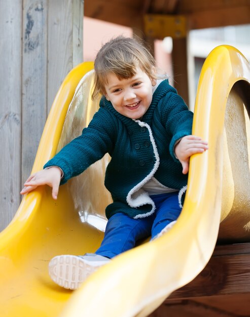 bambino felice sulla diapositiva al parco giochi