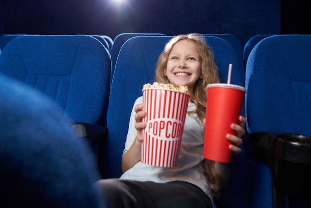 Bambino femminile felice che gode del film divertente in cinema