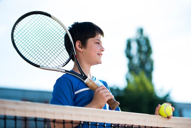 Bambino guardando lontano sul campo da tennis