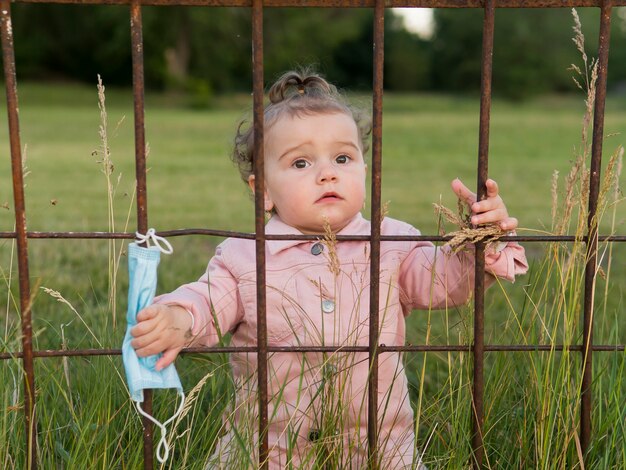 Bambino in abiti rosa dietro le sbarre del parco