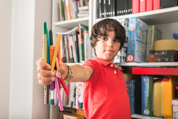 Bambino in piedi con le matite colorate