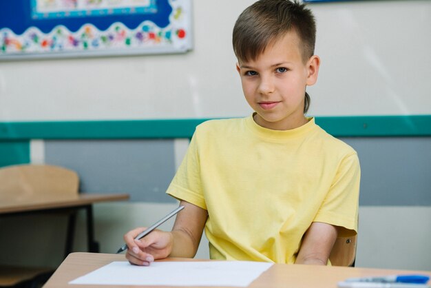 Bambino in posa con la penna a tavola