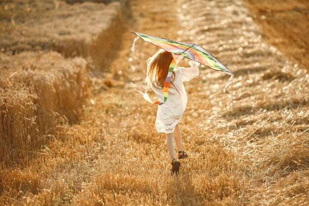 Bambino in un campo estivo. Bambina in un vestito bianco carino. Bambino con un aquilone.