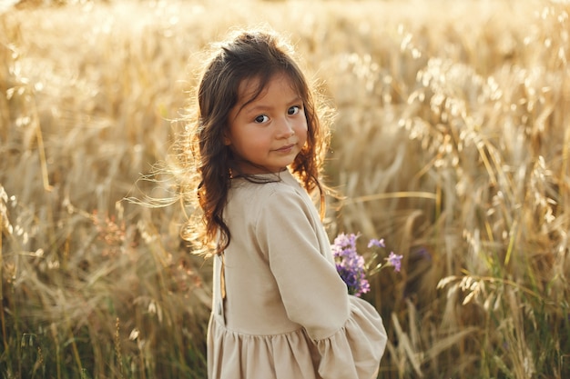 Bambino in un campo estivo. Bambina in un vestito marrone carino.